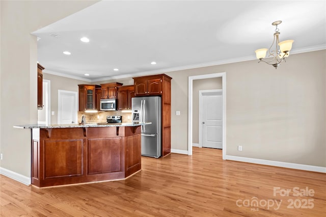 kitchen featuring light stone countertops, a notable chandelier, kitchen peninsula, decorative light fixtures, and appliances with stainless steel finishes