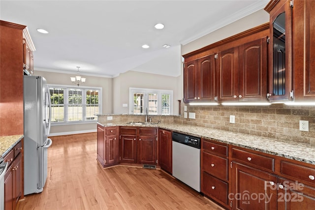 kitchen with sink, kitchen peninsula, a chandelier, decorative light fixtures, and appliances with stainless steel finishes