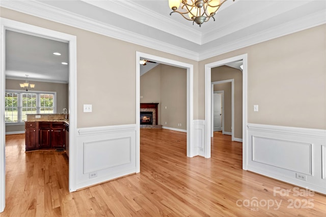 interior space with a high end fireplace, ceiling fan with notable chandelier, light hardwood / wood-style floors, and crown molding