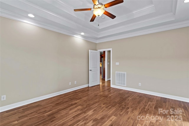 empty room with hardwood / wood-style flooring, ceiling fan, a raised ceiling, and ornamental molding