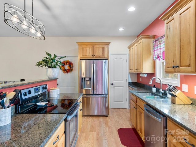 kitchen with appliances with stainless steel finishes, light wood-type flooring, sink, dark stone countertops, and hanging light fixtures