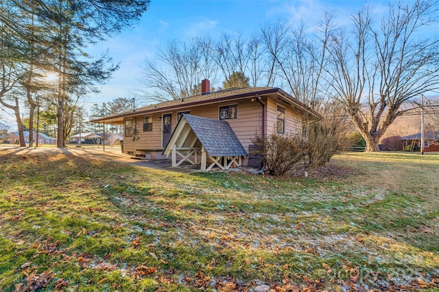 back of property featuring a lawn and an outbuilding