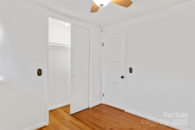 unfurnished bedroom featuring crown molding, ceiling fan, a closet, and wood-type flooring