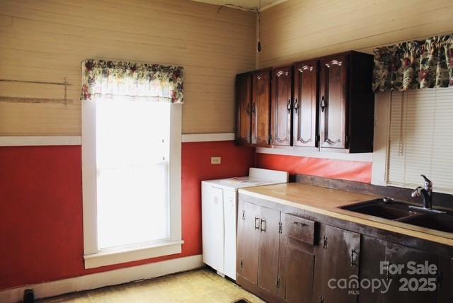 kitchen featuring independent washer and dryer, dark brown cabinets, and sink