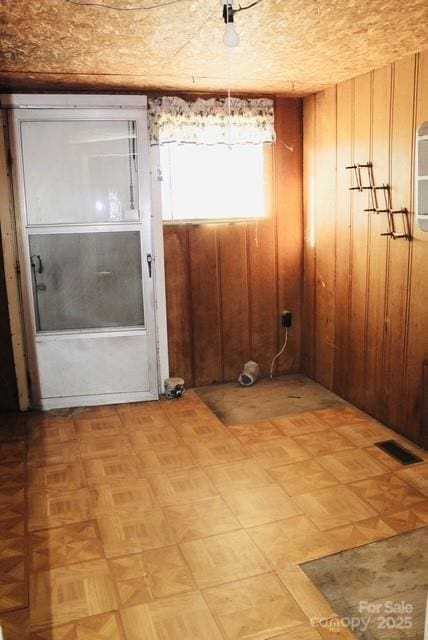 unfurnished room featuring wood walls and light parquet floors