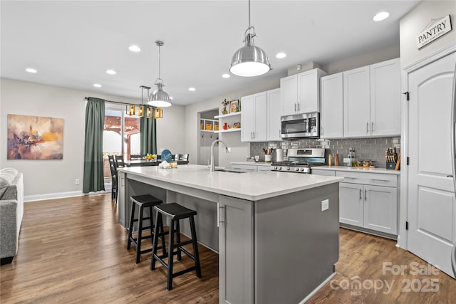 kitchen featuring a kitchen bar, white cabinets, an island with sink, and stainless steel appliances