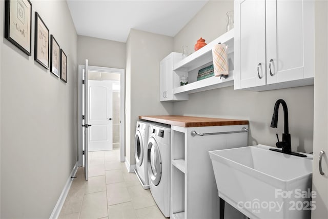 clothes washing area featuring separate washer and dryer, sink, light tile patterned flooring, and cabinets