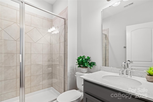 bathroom featuring vanity, toilet, and a shower with door