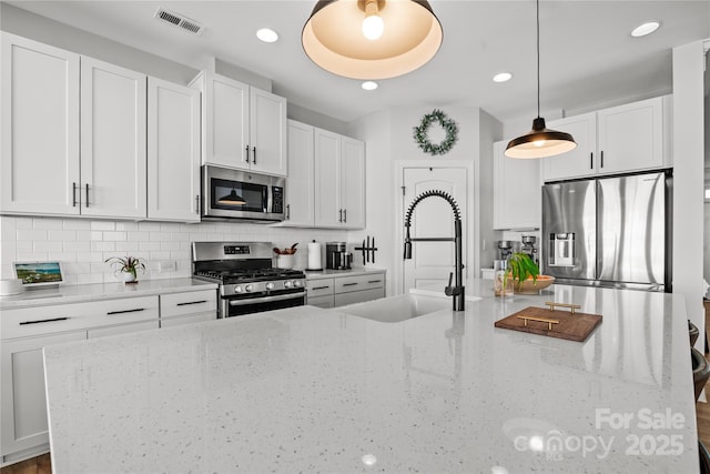 kitchen featuring light stone countertops, pendant lighting, and stainless steel appliances