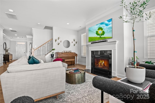 living room featuring wood-type flooring, crown molding, and a wealth of natural light