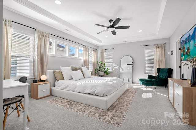 bedroom featuring light carpet, a tray ceiling, and ceiling fan