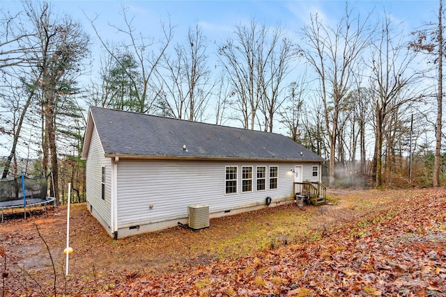 back of house with a trampoline and central AC