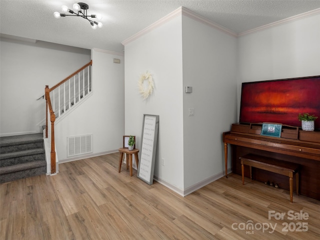 interior space featuring ornamental molding, a textured ceiling, light hardwood / wood-style flooring, and a notable chandelier