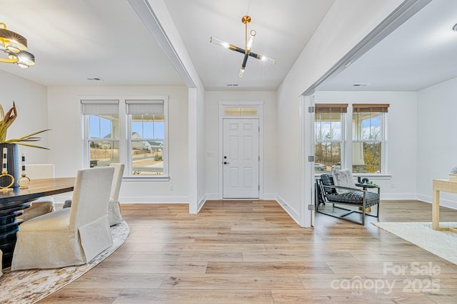 foyer entrance with a healthy amount of sunlight, a notable chandelier, and light wood-type flooring