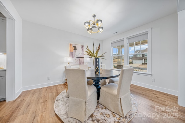 dining space with light hardwood / wood-style flooring and a chandelier