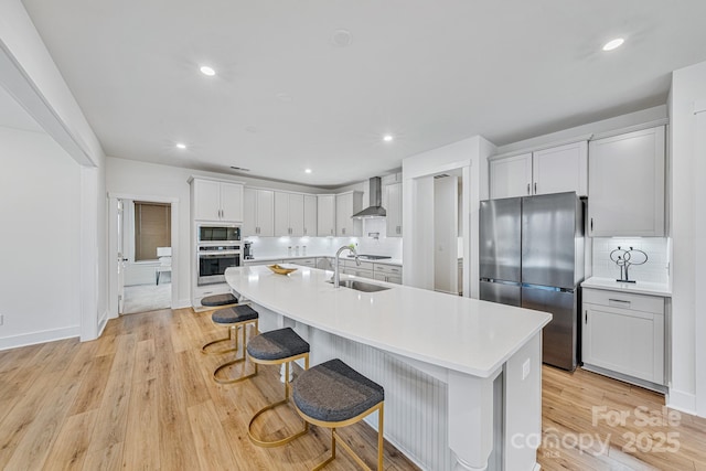 kitchen with wall chimney exhaust hood, a kitchen bar, stainless steel appliances, an island with sink, and backsplash