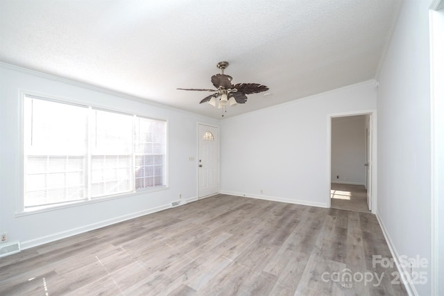 spare room with a textured ceiling, light wood-type flooring, ceiling fan, and ornamental molding