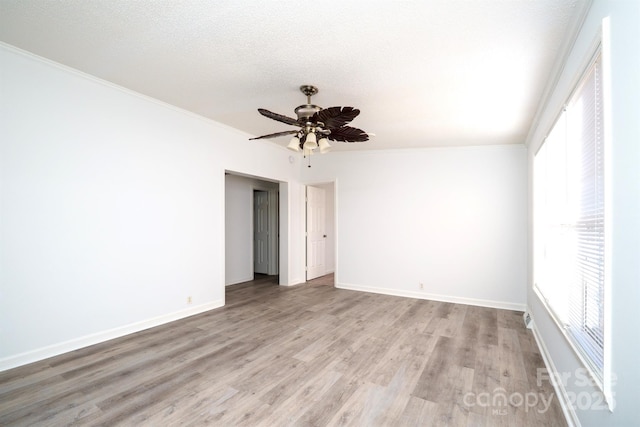 unfurnished room featuring a wealth of natural light, light hardwood / wood-style flooring, a textured ceiling, and ornamental molding