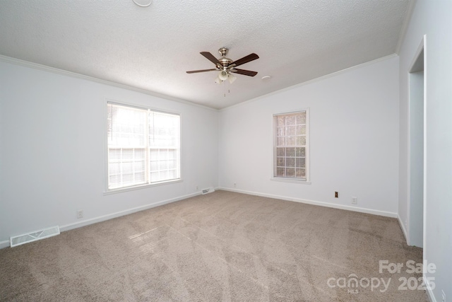 empty room with ceiling fan, crown molding, a textured ceiling, and light carpet