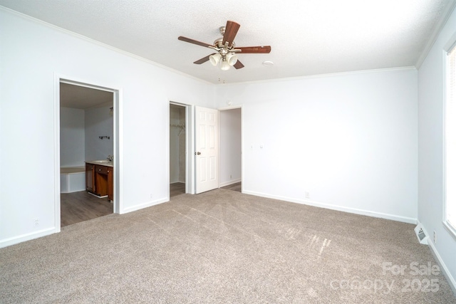 unfurnished bedroom with connected bathroom, ceiling fan, crown molding, carpet floors, and a closet