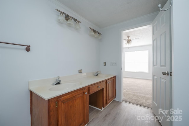 bathroom with ceiling fan, ornamental molding, a textured ceiling, vanity, and hardwood / wood-style flooring