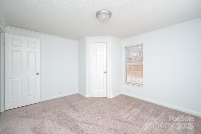 spare room with light carpet, a textured ceiling, and ornamental molding