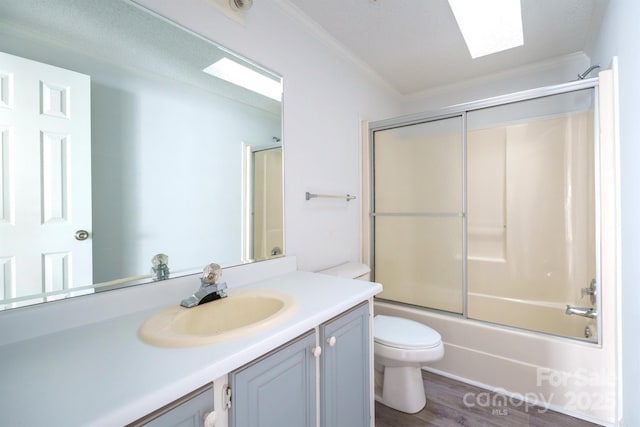 full bathroom featuring vanity, shower / bath combination with glass door, crown molding, a skylight, and toilet