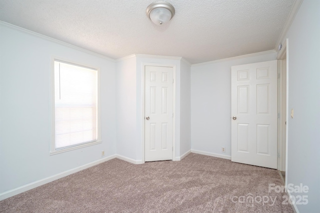 unfurnished bedroom with a textured ceiling, ornamental molding, and light carpet