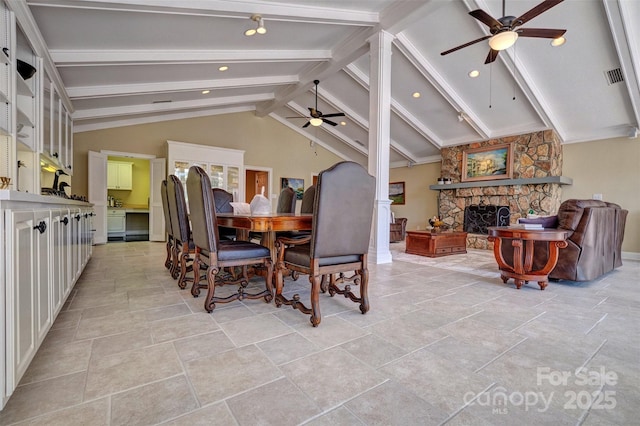 dining room with lofted ceiling with beams, a stone fireplace, and ceiling fan