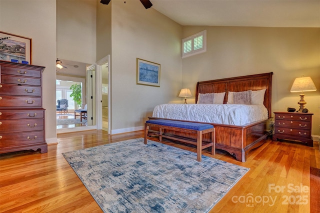 bedroom featuring ceiling fan, light hardwood / wood-style floors, high vaulted ceiling, and ensuite bath