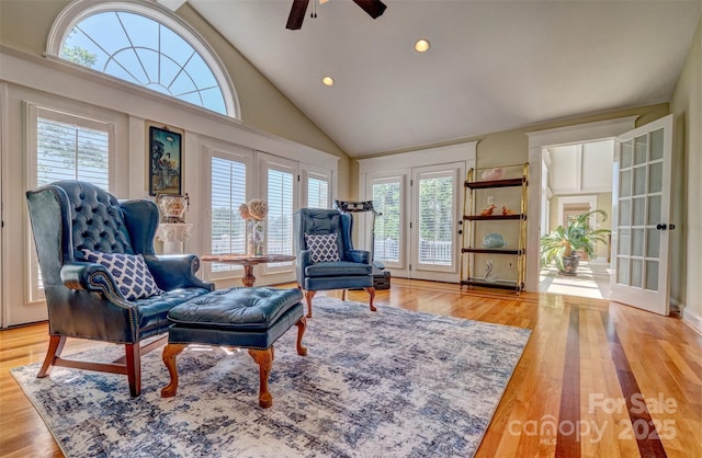 sitting room with light wood-type flooring, high vaulted ceiling, ceiling fan, and a healthy amount of sunlight