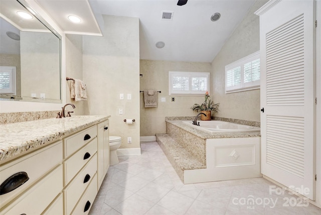 bathroom featuring vanity, vaulted ceiling, tile patterned flooring, tiled bath, and toilet