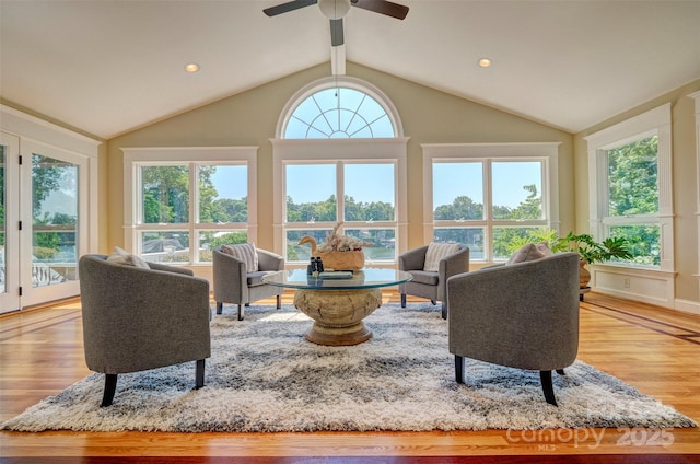 living room with ceiling fan, lofted ceiling, and light hardwood / wood-style flooring