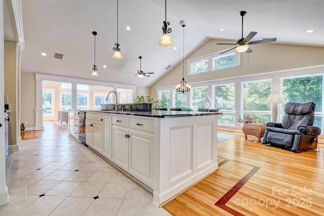 kitchen with white cabinetry, a center island with sink, light tile patterned floors, and hanging light fixtures