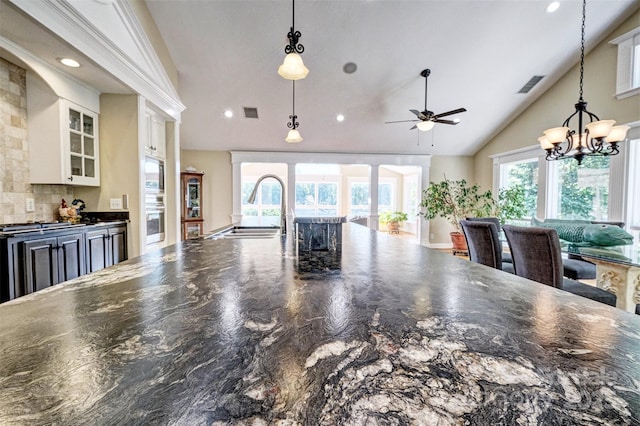 kitchen with backsplash, lofted ceiling, sink, and decorative light fixtures