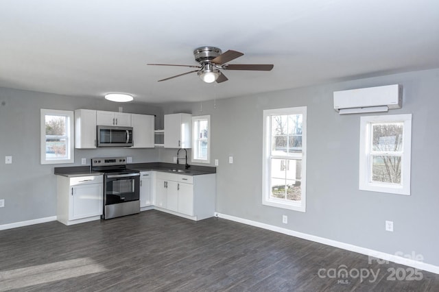 kitchen featuring stainless steel appliances, sink, white cabinets, a wall unit AC, and dark wood-type flooring