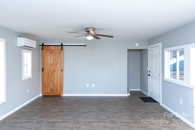 unfurnished room with a healthy amount of sunlight, ceiling fan, a barn door, and a wall unit AC