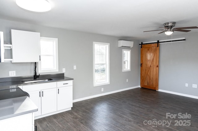 kitchen featuring a barn door, plenty of natural light, white cabinets, ceiling fan, and a wall mounted air conditioner