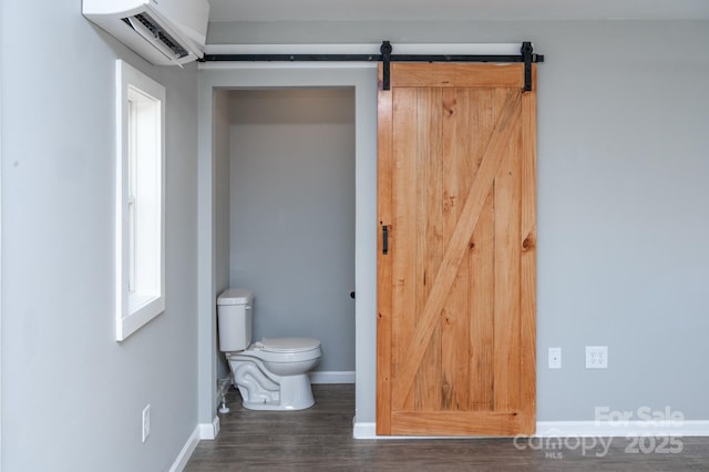 bathroom featuring hardwood / wood-style flooring, a wall unit AC, and toilet