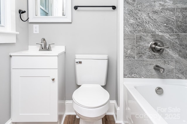 bathroom featuring toilet, a tub to relax in, and vanity