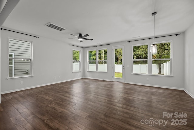 empty room with dark hardwood / wood-style flooring, ceiling fan, and plenty of natural light