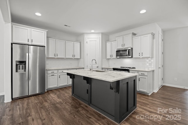 kitchen with white cabinetry, stainless steel appliances, light stone countertops, and sink