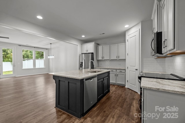 kitchen with sink, stainless steel appliances, a kitchen island with sink, and light stone counters