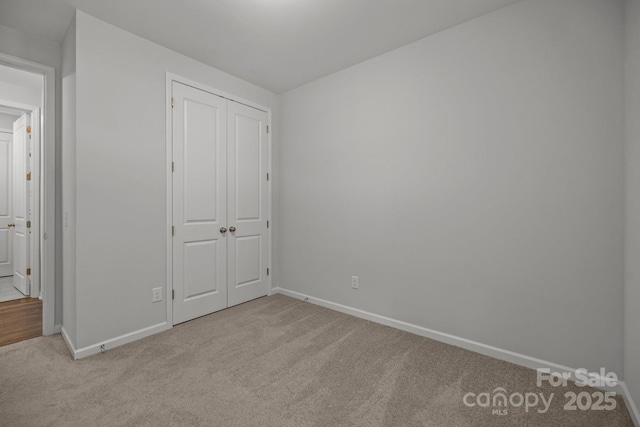 unfurnished bedroom with a closet and light colored carpet