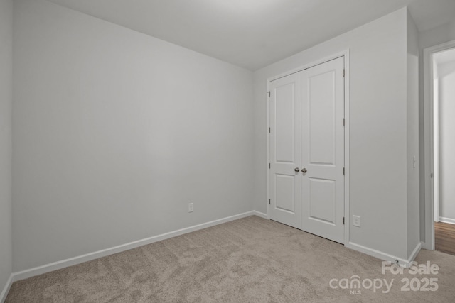 unfurnished bedroom with a closet and light colored carpet