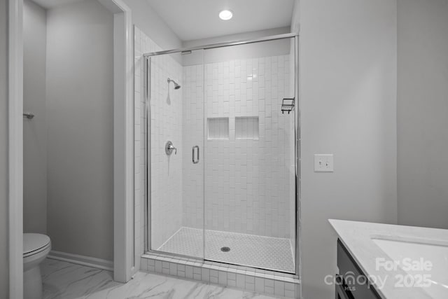 bathroom featuring toilet, vanity, and a shower with door