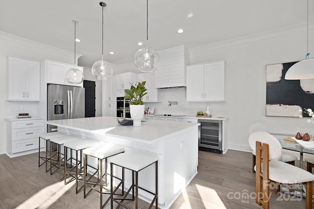 kitchen with white cabinetry, stainless steel appliances, wine cooler, pendant lighting, and a kitchen island