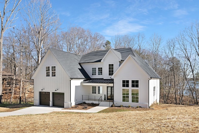 modern inspired farmhouse featuring covered porch, a front yard, and a garage