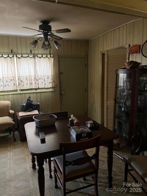 dining room with ceiling fan and wooden walls