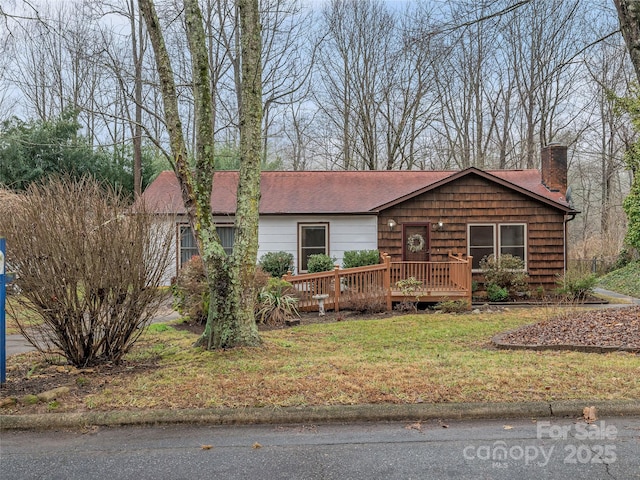 ranch-style home featuring a wooden deck and a front yard